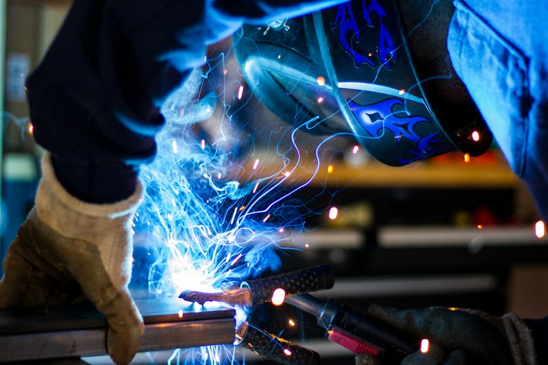 Welder in a protective helmet working on steel