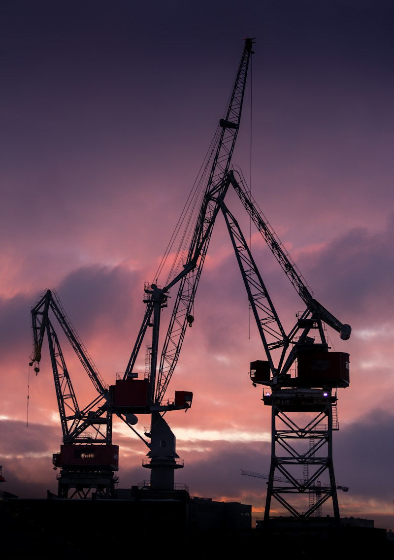 Shipyard cranes silhouetted at dusk