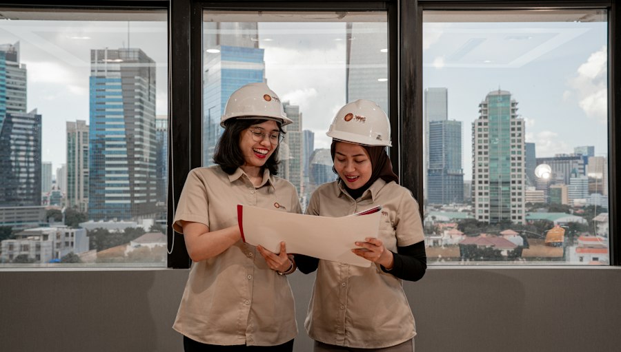 Two engineers in hard hats reviewing drawings